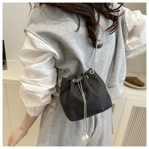 Close-up of black crocodile-embossed bucket bag with silver chain and pearl drawstrings