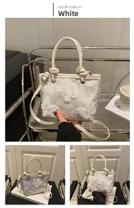 Détail du sac seau blanc brodé avec appliqués de fleurs papillons 3D et poignée ronde