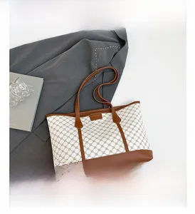 Close-up of printed tote bag showing brown monogram pattern and leather patch detail