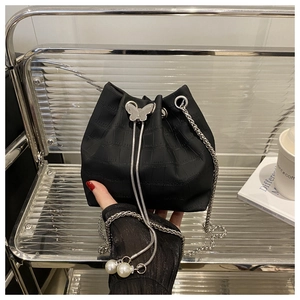 Detail of black faux crocodile bucket bag with silver butterfly clasp and pearl drawstrings