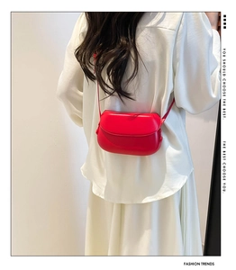 Close-up of a minimalist red saddle bag showing smooth matte leather and adjustable strap