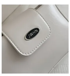 Nahaufnahme der cremefarbenen PU-Lederhandtasche mit ovaler schwarzer JWHN-Metallplakette