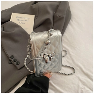 Close-up of silver quilted phone bag with metallic bow clasp on a grey blazer background