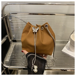 Detail of brown crocodile pattern bucket bag with silver butterfly and pearl drawstring