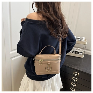 Vue portée d'un sac seau beige structuré avec logo M doré et bandoulière réglable