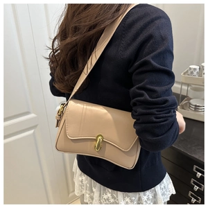 Detailansicht der beigen Leder-Schultertasche mit Goldschloss am weiblichen Model