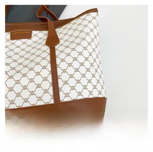 Detail showing high-quality stitching on white faux leather tote with brown monogram