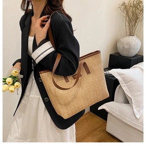 Détail d'un grand sac cabas en paille tissée avec des anses en cuir marron pour l'été