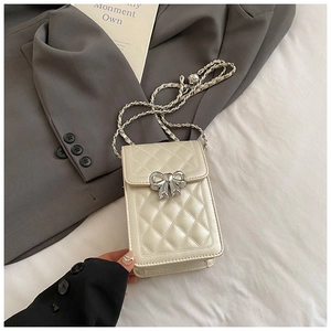 Close-up of quilted cream phone bag with silver bow clasp and elegant chain strap