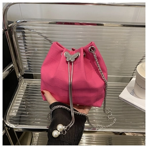 Detail of pink croc-embossed bucket bag with silver butterfly buckle and pearl chain
