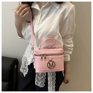 Detailed shot of a pink cylinder bag with a gold metal M logo and a top handle
