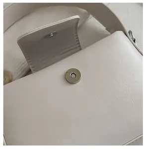 Detailansicht der hochwertigen silbernen Magnetschnalle an der weißen minimalistischen Handtasche