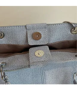 Detailsicht des silbernen Magnetverschlusses einer gewebten hellblauen Jeans-Tote-Bag