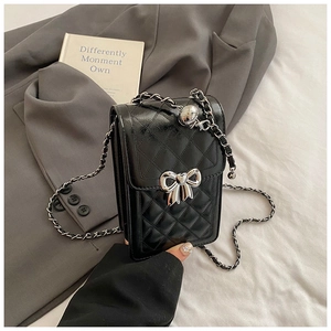 Close-up of black quilted mini bag with silver chain strap and metal bow detail