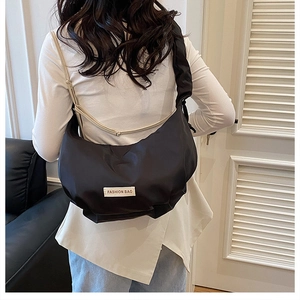 Rear view of black nylon dumpling bag with pleated strap and Fashion Bag logo tag