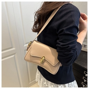 Detail einer beigen Leder-Achseltasche mit goldener Schnalle und verstellbarem Gurt