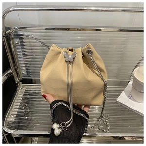 Detailed macro of beige croc-embossed bucket bag with silver butterfly buckle and pearl chain