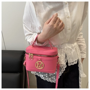 Détail du sac boîte fuchsia montrant le logo M métallique et le cuir lisse avec poignée haute