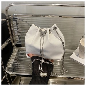 Close-up of white croc-embossed bucket bag with silver butterfly and pearl charms