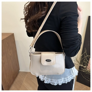 Nahaufnahme der cremefarbenen Achseltasche aus Glanzleder mit Logo an einem Modell