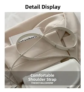 Detail showing the adjustable leather shoulder strap on the chic cream underarm bag