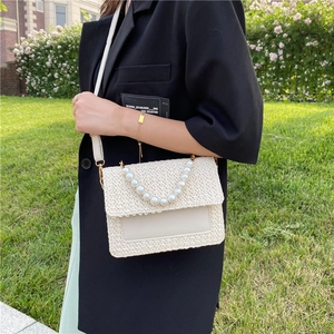 Chic beige woven straw handbag featuring a large pearl handle and adjustable shoulder strap