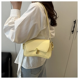 Hellgelbe Leder-Schultertasche mit goldenem Verschluss zu weißem Hemd und Jeans
