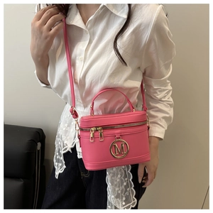 Détail du sac seau rose avec logo métallique doré lettre M et poignée supérieure