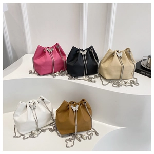 Detail of five multi-colored bucket bags with butterfly buckles and pearl metal chains