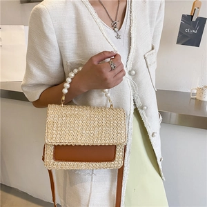 Straw crossbody bag with pearl handle and brown leather trim shown on model