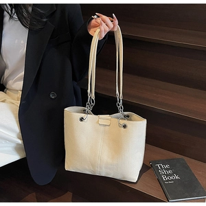 Detail of beige canvas tote bag showing silver chain strap and durable woven texture