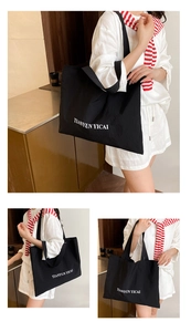 Detail view of large black canvas tote bag with white letter print on durable fabric