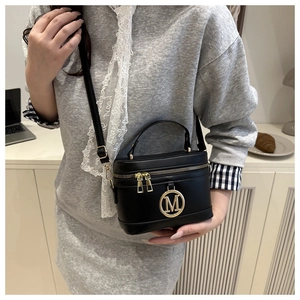 Detailed close-up of a black bucket bag with gold M-logo and double zippers