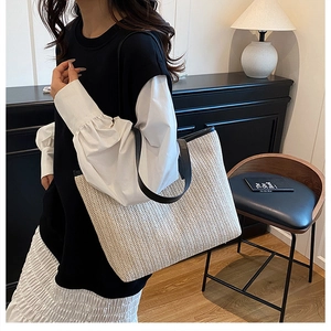 Détail du sac cabas en paille à chevrons avec poignées en cuir noir dans un décor intérieur