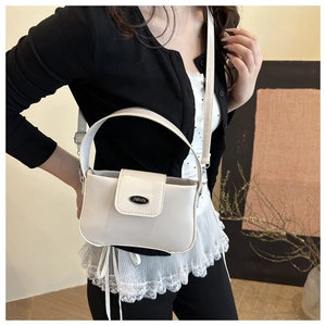 Detailansicht der weißen Kunstledertasche mit schwarzer Metallplakette und Handgriff