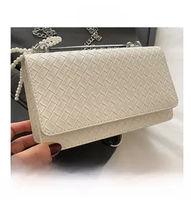 Detail of white woven leather handbag featuring pearl strap and silver chain accents