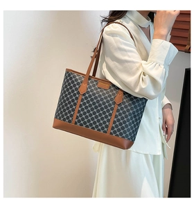 Detail of large tote bag with dark grey monogram pattern and brown leather straps