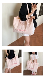 Three-way view of a large pink canvas tote bag with red letter print and long straps