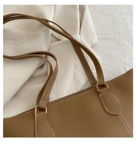 Close-up of brown tote bag showing contrast stitching and gold hardware detail