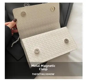 Close-up of dual silver magnetic buckles on a white woven leather flap bag detail