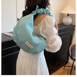 Close-up of a light blue nylon cloud bag with pleated straps on a white dress model