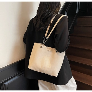 Close-up of beige faux leather tote bag with silver metal chain details on shoulder strap