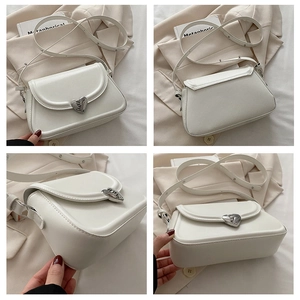 Detail view of white crossbody bag with silver heart buckle and smooth leather texture