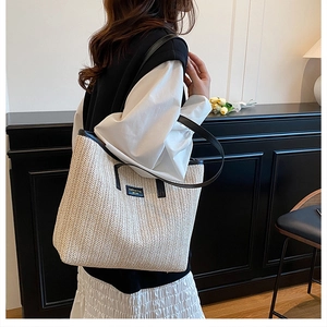 Detail of the woven straw texture and stylish black leather strap on a large summer tote