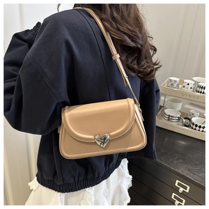 Detail of light khaki leather crossbody bag with silver heart-shaped magnetic clasp