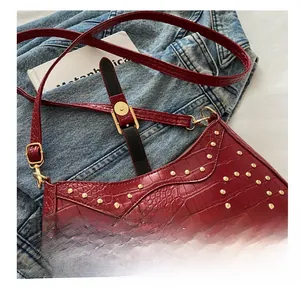 Detail of dark red crocodile pattern bag with gold rivets and magnetic closure buckle