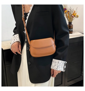 Detail of vintage brown leather crossbody saddle bag with rounded flap and sleek strap