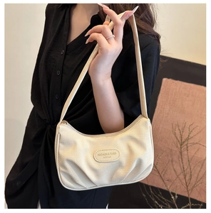 Donna con un'elegante borsa a spalla plissettata bianco crema con patch logo