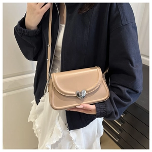 Detail of apricot crossbody bag with silver heart magnetic clasp shown on a model