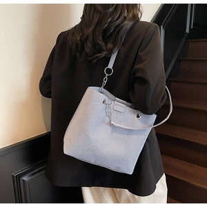 Close-up of light blue denim bucket bag featuring silver metal rings and textured fabric